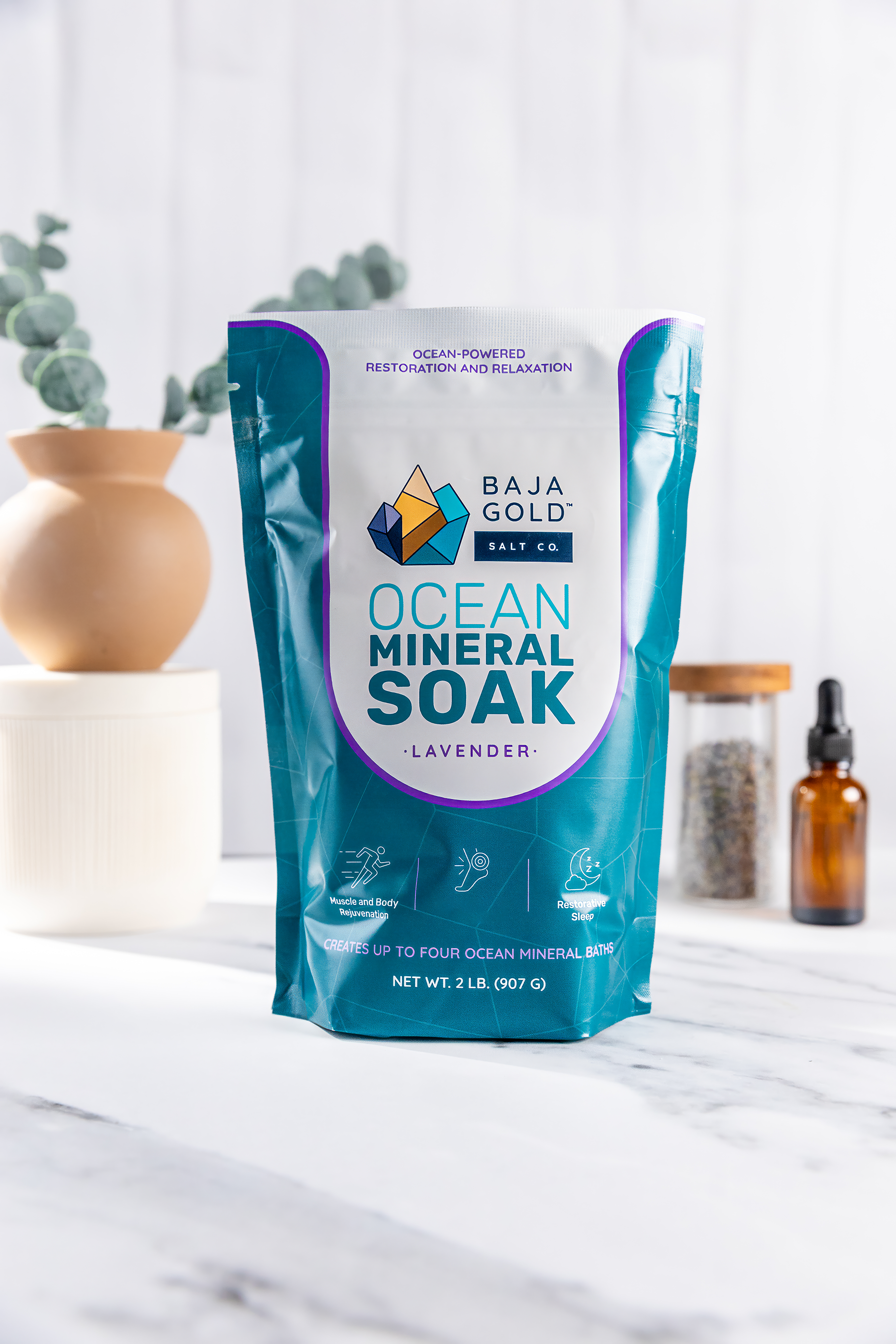 Baja Gold ocean mineral soak lavender package on a marble surface with decorative items in the background.